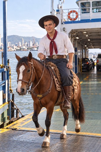 A person riding a brown horse through a modern indoor arena.