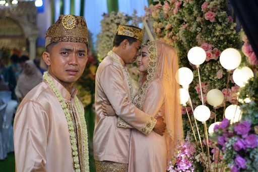 People in traditional attire celebrating beside floral decorations and glowing lights