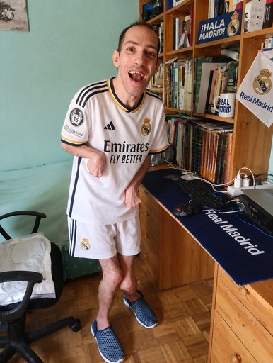 Person wearing a white soccer jersey standing beside a desk in a room